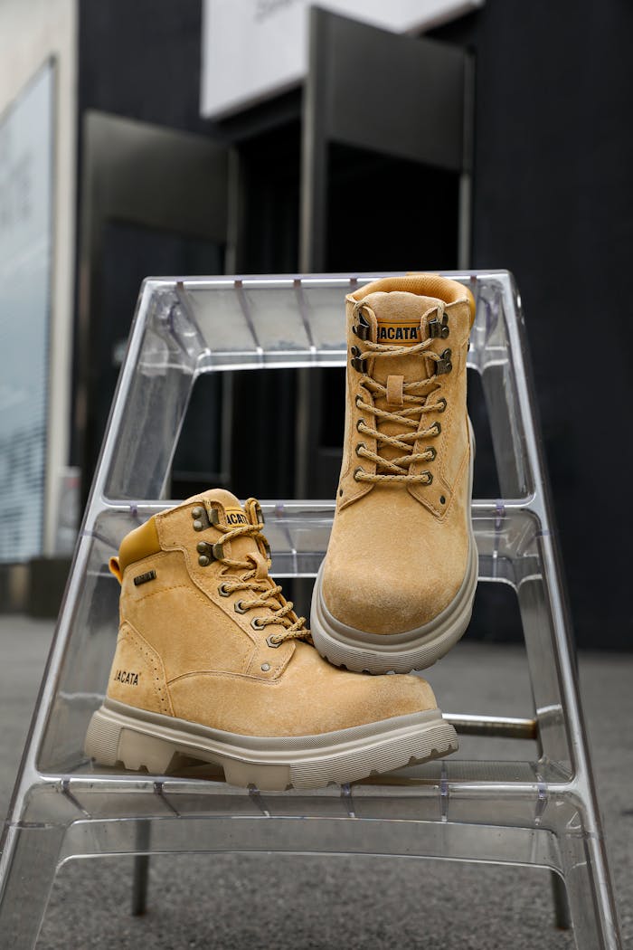 Services Modern tan leather boots showcased on a clear acrylic ladder indoors.