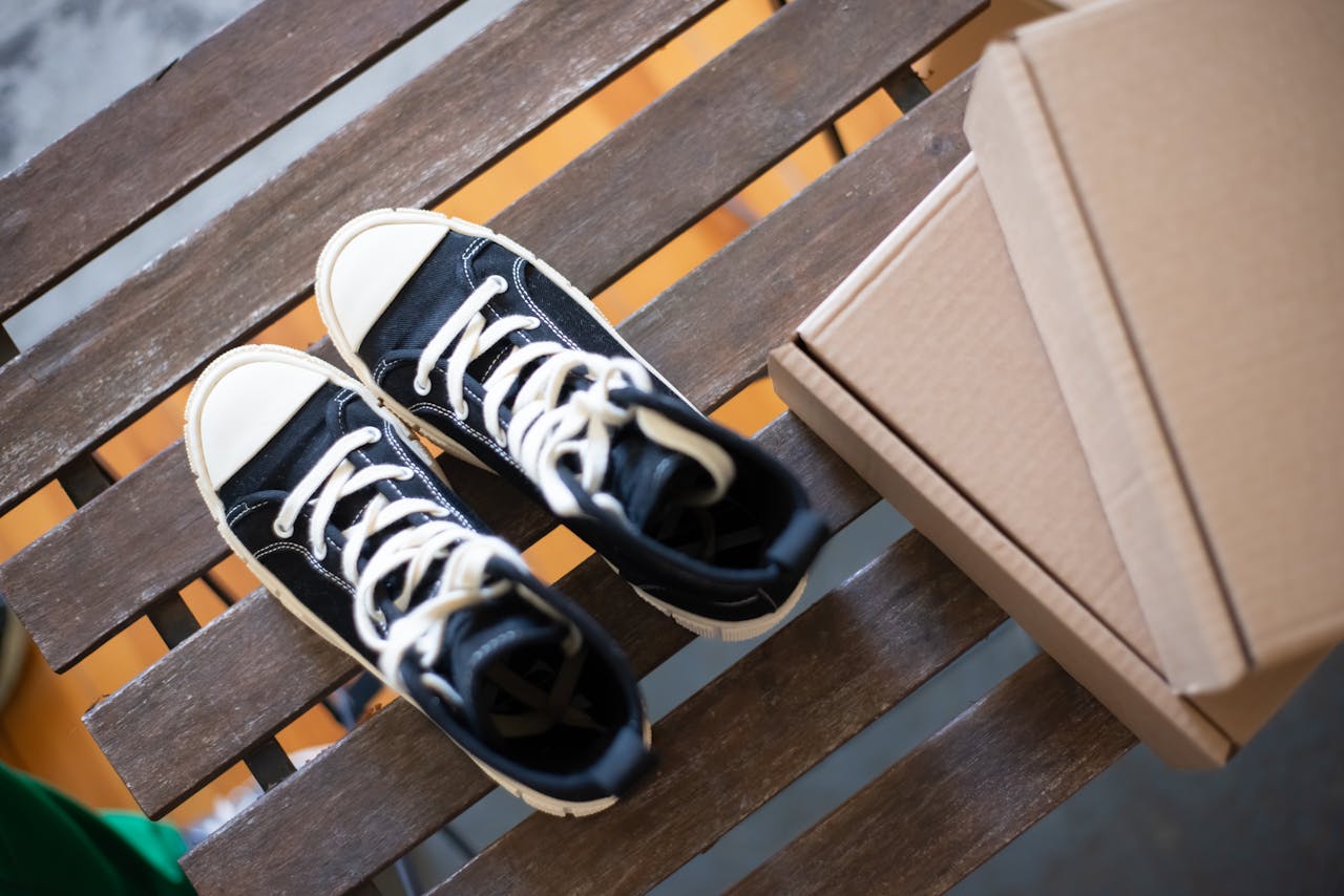 Services Stylish high top sneakers on a rustic wooden bench with cardboard boxes. Perfect for fashion shoots.