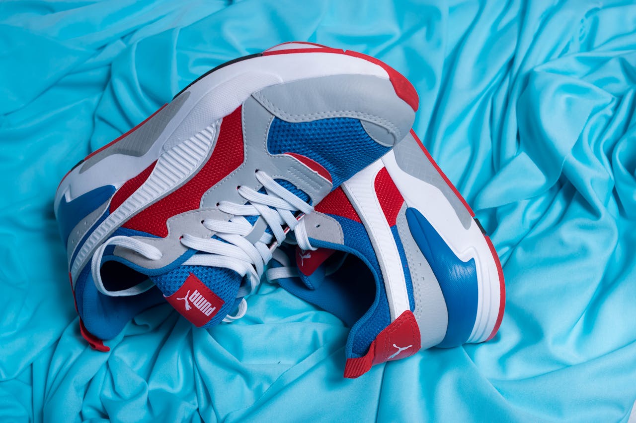 Top view of pair of modern sneakers made in creative design for trainings on blue fabric